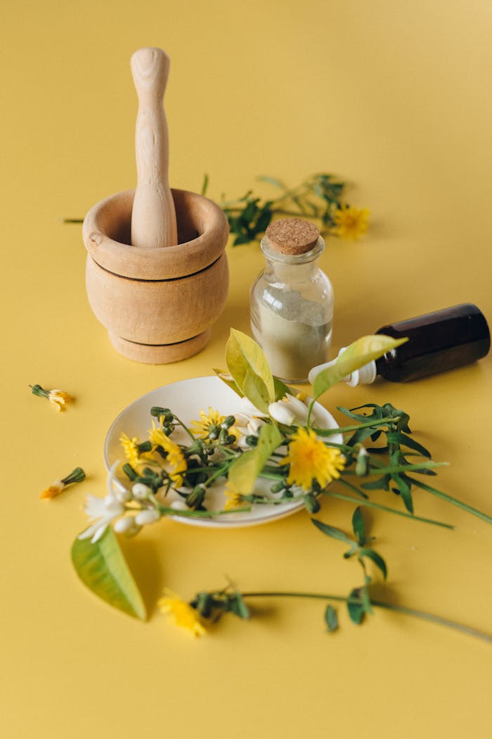services-03 Ingredients for a natural herbal remedy with a mortar, pedestal, and bottle on a yellow surface.
